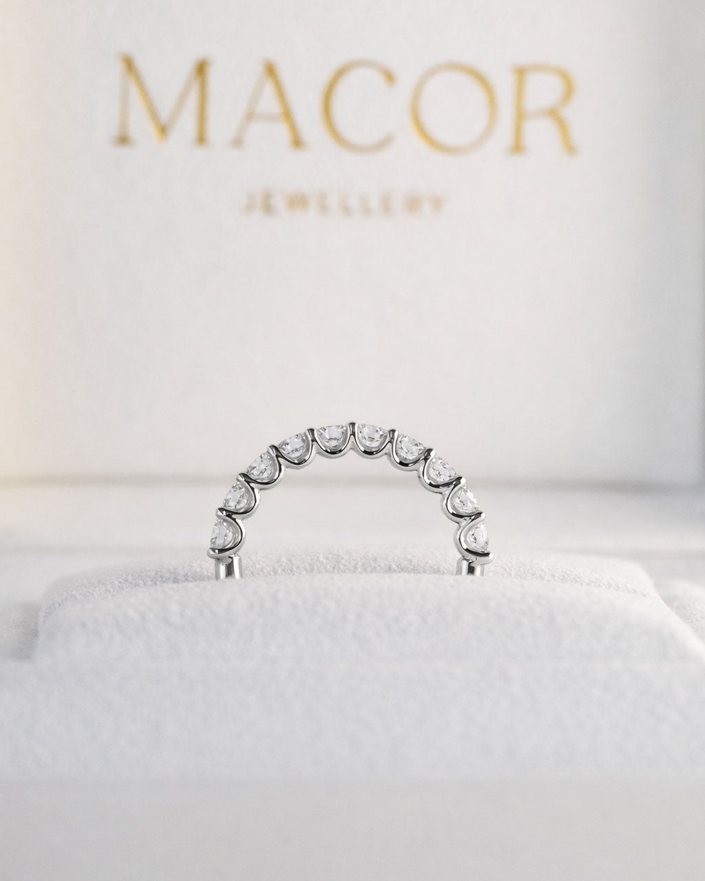 Silver ring with clear stones on a white cushion with 'MACOR Jewellery' branding.